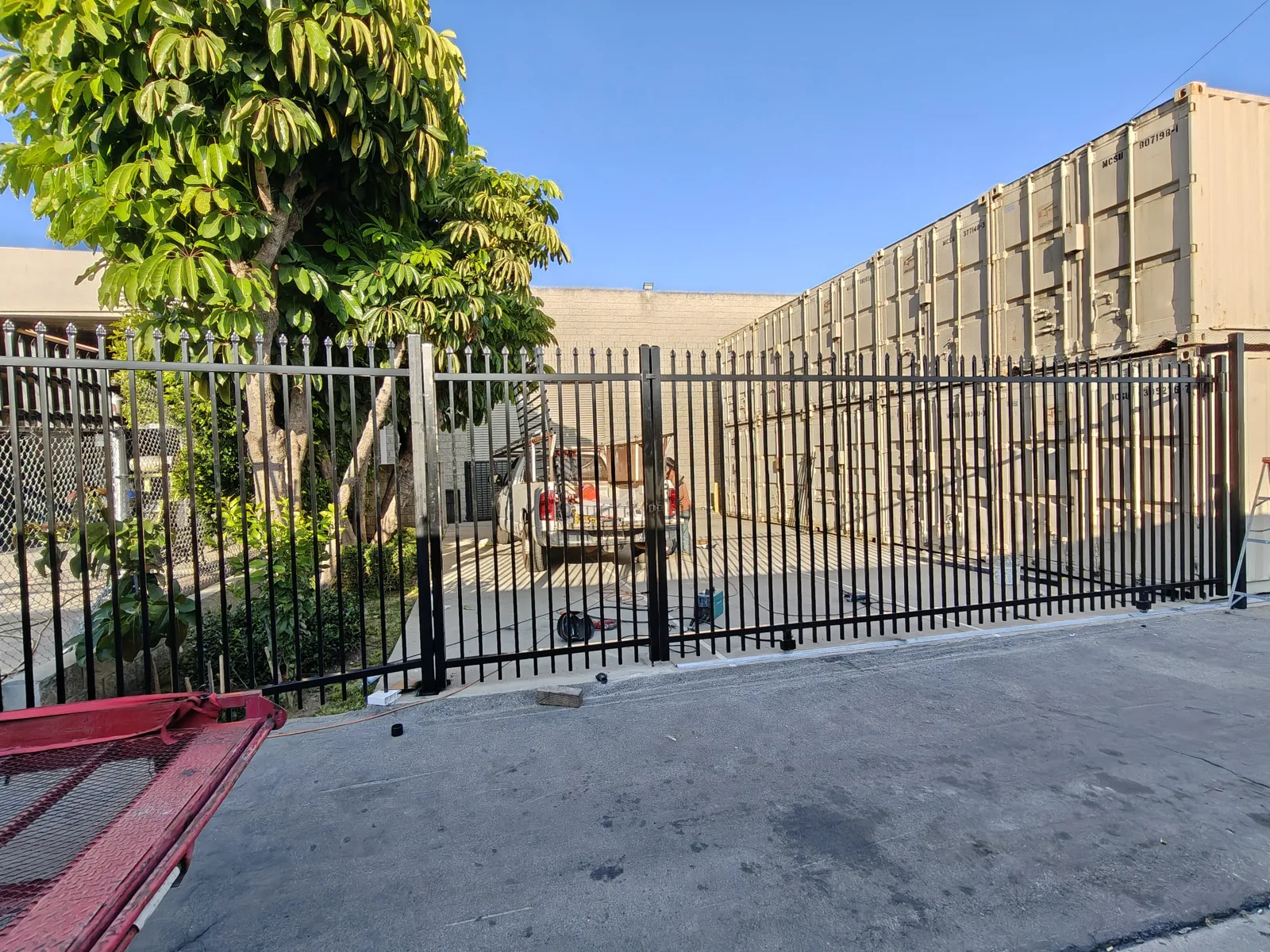 20-foot double-swing black steel security gate at a commercial yard in Los Angeles by Apexguard Fence