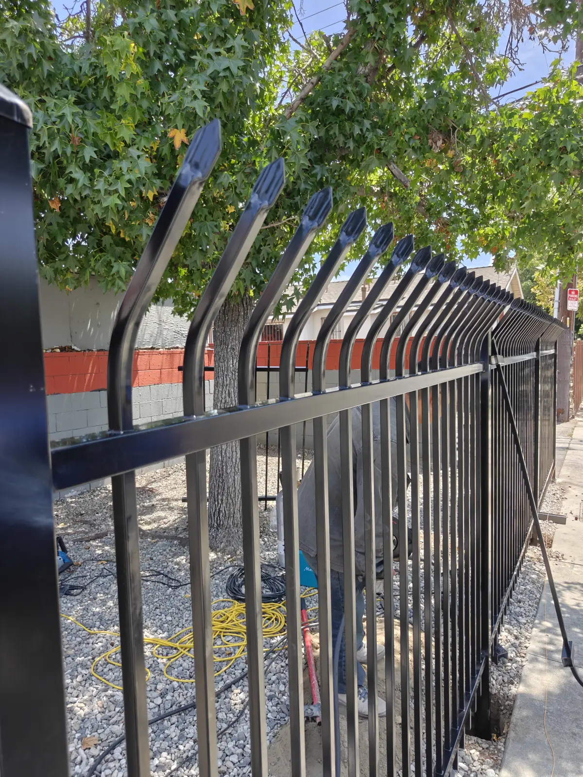 Close-up of black steel security fence with anti-climb bent-spear tops installed in Bell Gardens, CA