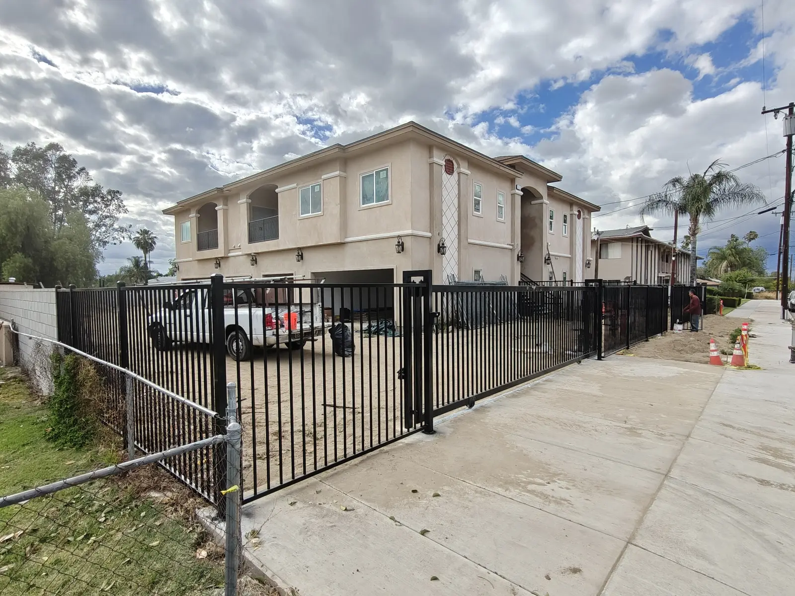 Black steel perimeter fence and automatic sliding driveway gate around a new two-story condo community in Fontana, CA, by Apexguard Fence