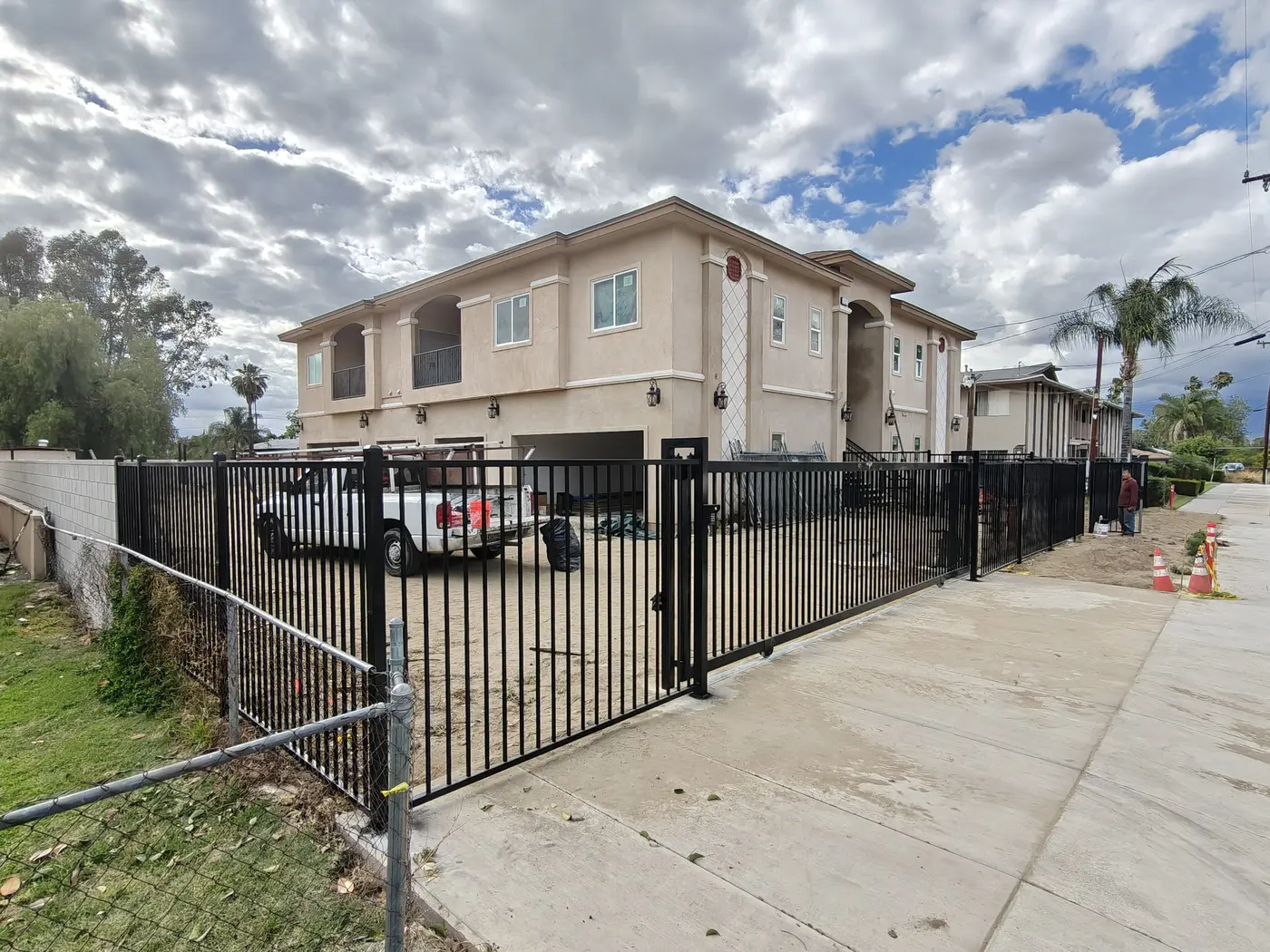 Corner of a black steel perimeter fence wrapping the side property line of a Fontana condo community