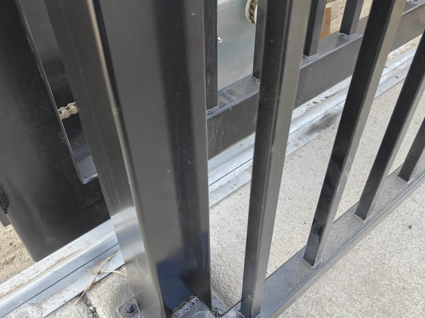 Chain-drive slide gate operator and gate post detail on an automatic driveway gate in Fontana, CA