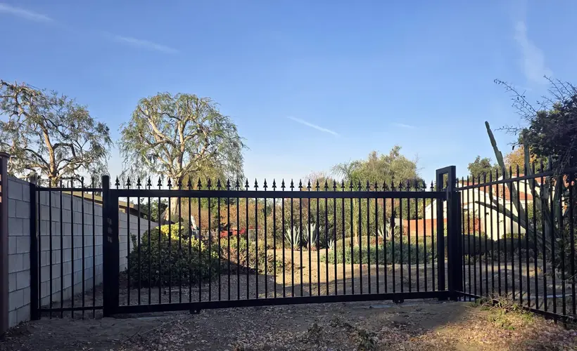 Spear-top iron sliding driveway gate next to masonry wall