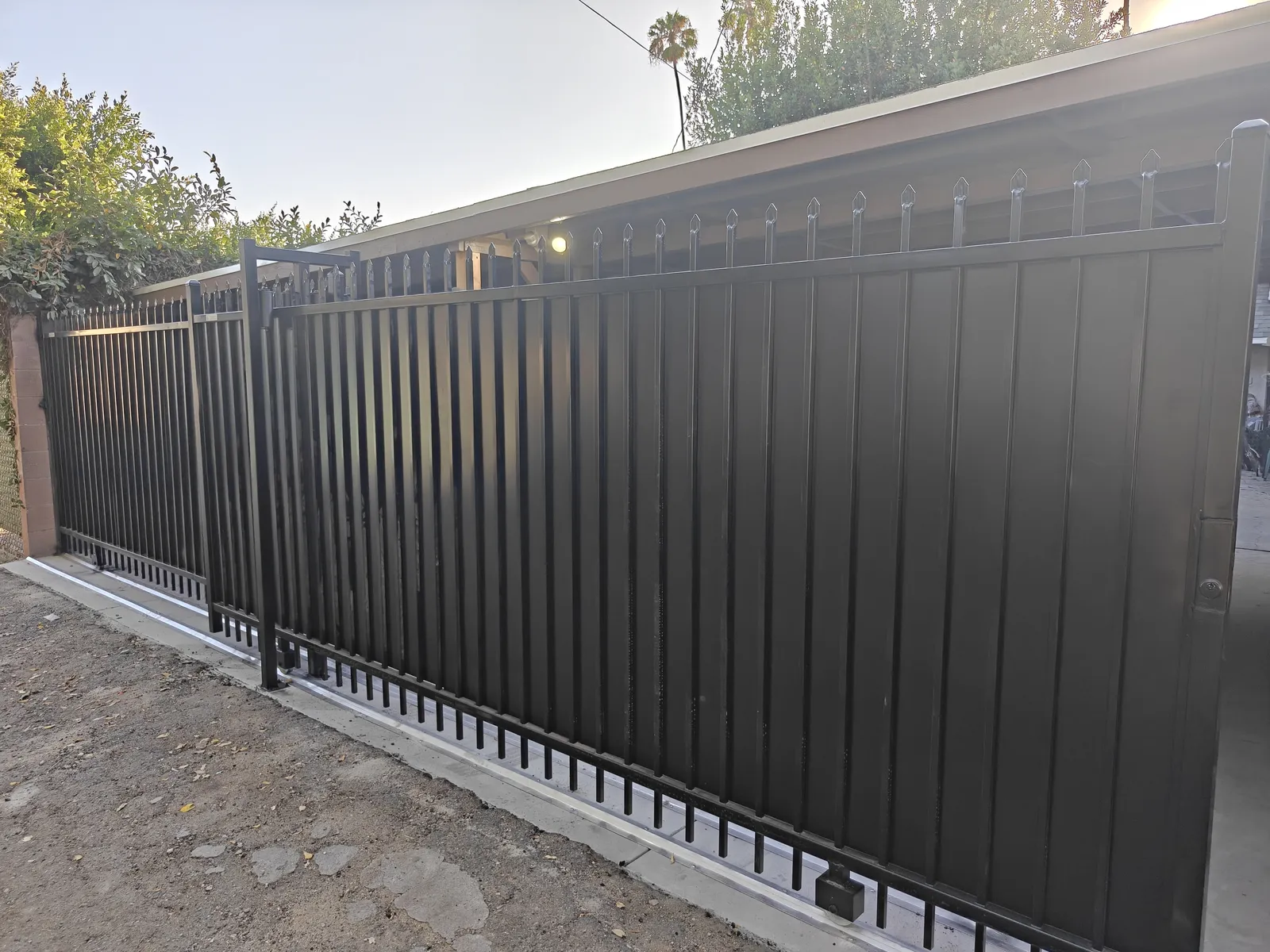 Two completed steel sliding security gates from a single driveway opening in Los Angeles