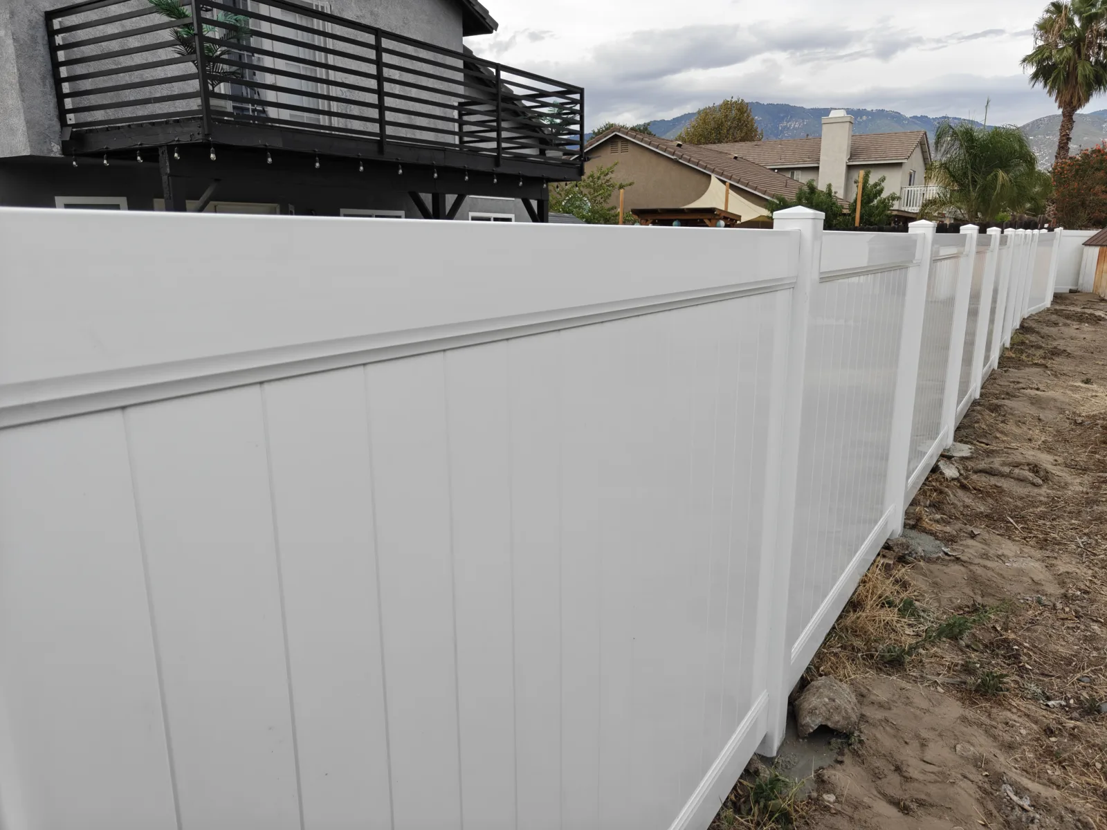 Corner detail of stepped white vinyl privacy fence panels in San Bernardino, CA by Apexguard Fence