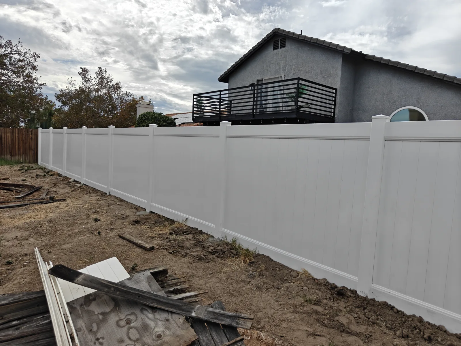 White vinyl privacy fence replacing a torn-out wood fence in San Bernardino, CA by Apexguard Fence