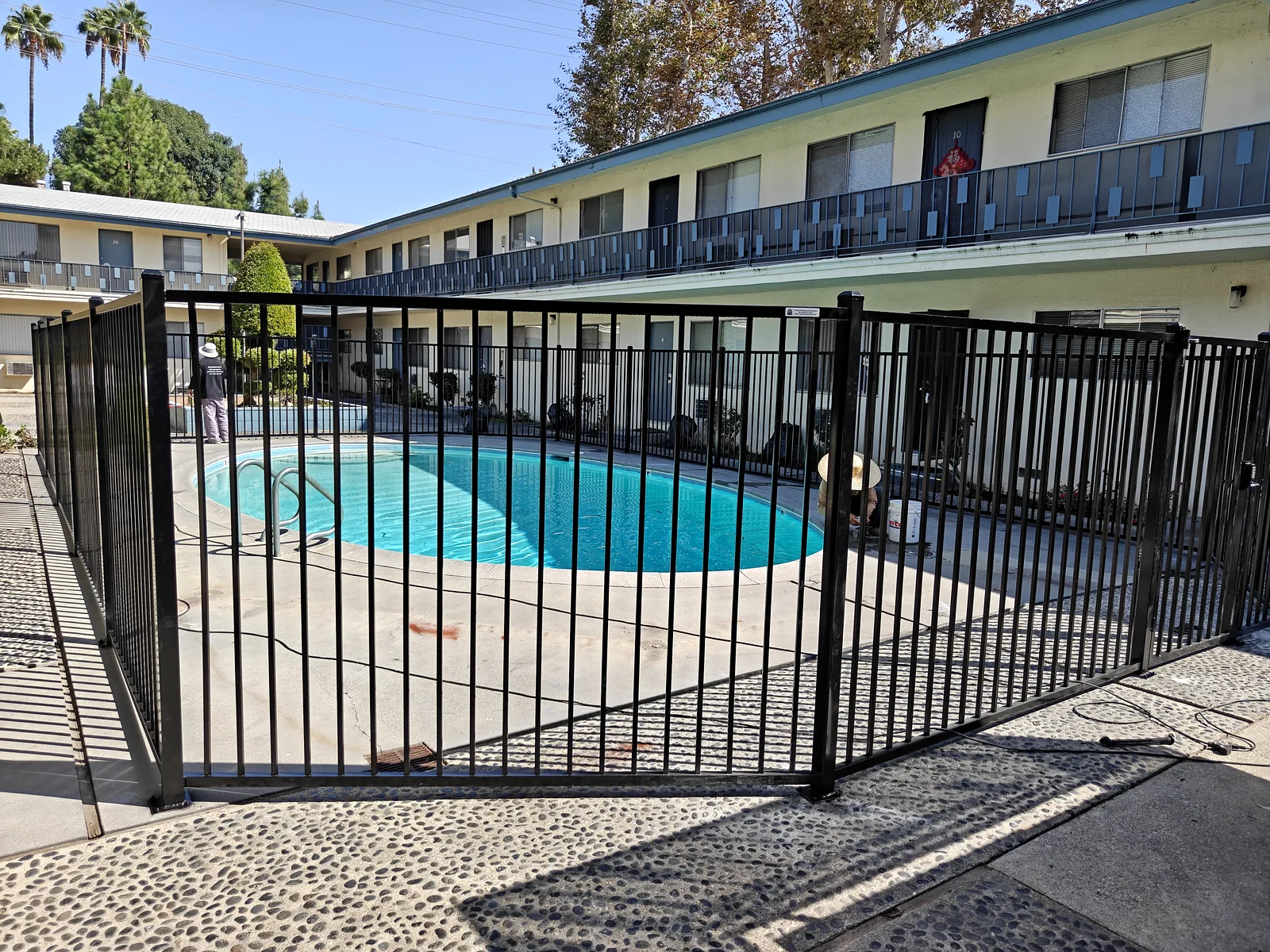 Black iron pool gate and fence panels at ground level at a West Covina apartment pool by Apexguard Fence