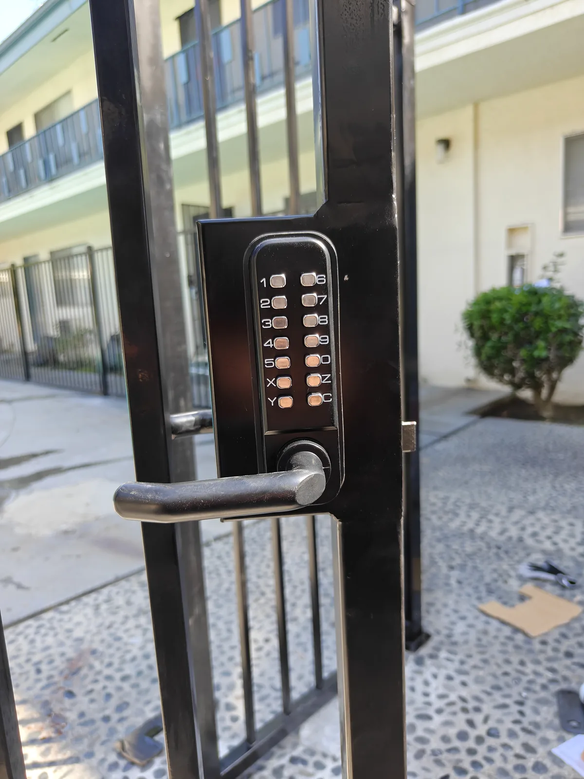 Keypad lock on a black iron pool gate at a West Covina apartment complex by Apexguard Fence