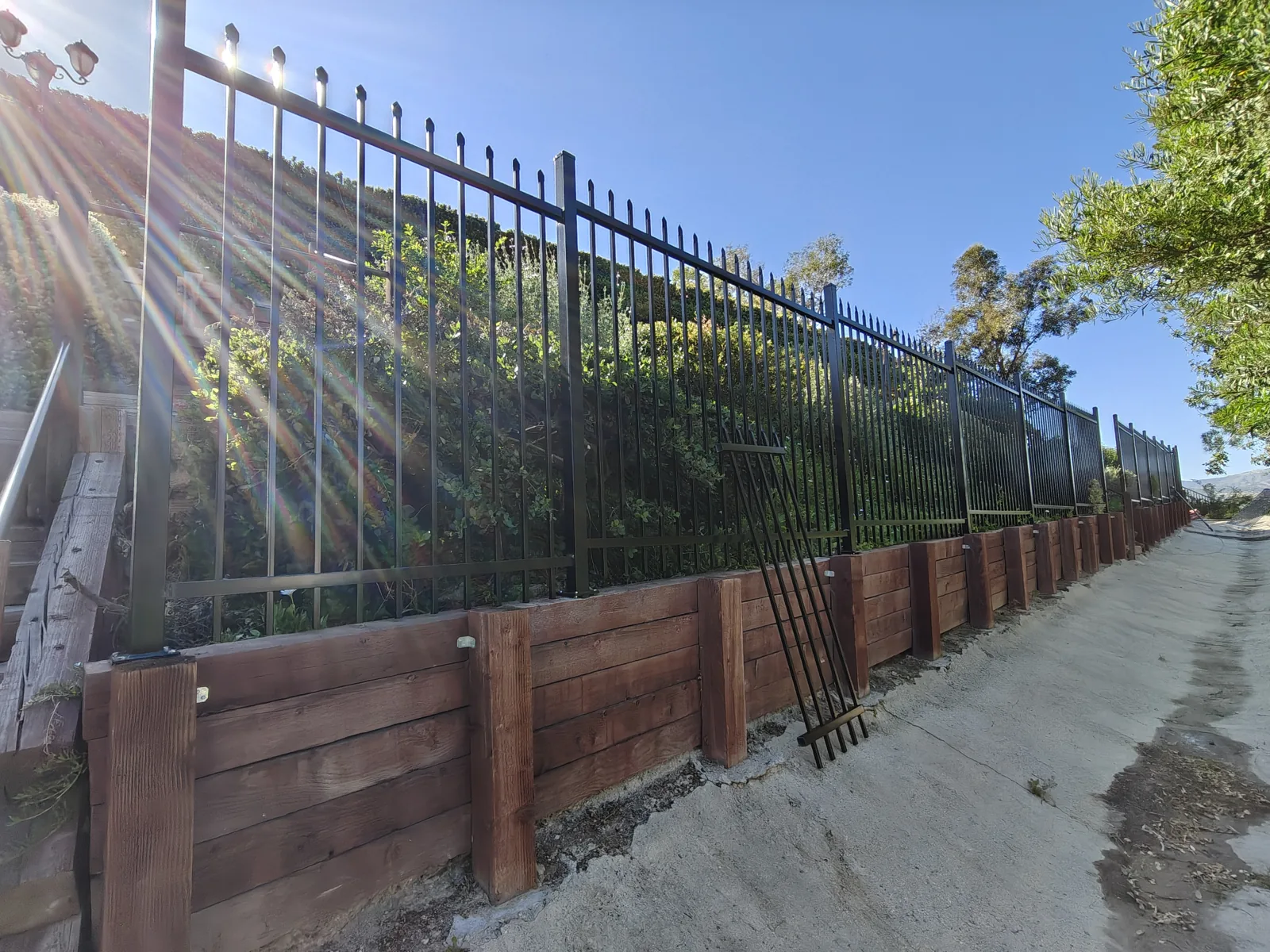 Long run of 6-foot wrought iron fence along a hillside retaining wall in West Hills, CA by Apexguard Fence