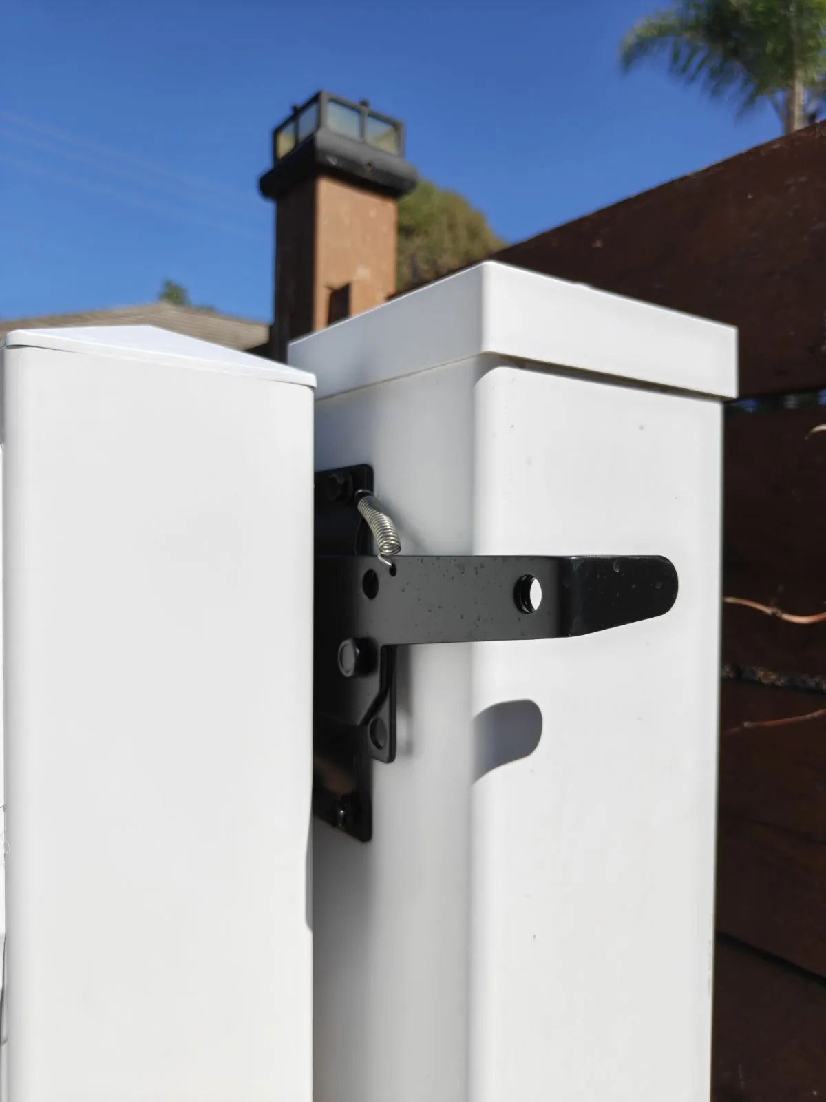Black gravity latch on a white vinyl gate in Whittier, CA by Apexguard Fence